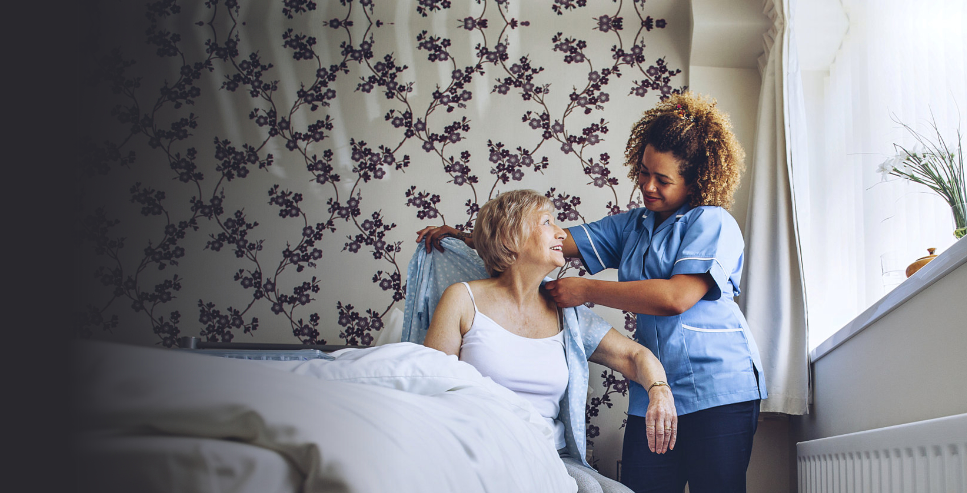caregiver helping senior woman to put on clothes