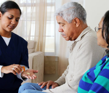 caregiver giving medicine to the elderly couple