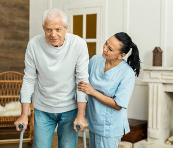 caregiver assissting elder man to walk
